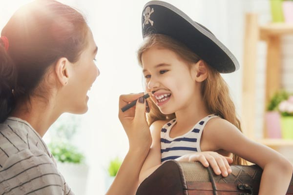 Mom drawing a moustache on a girl in a pirate’s costume