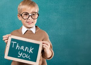 Bespectacled young boy holding ‘Thank You’ sign