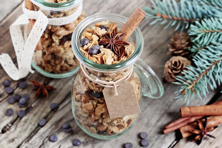 Granola in jars with cinnamon, chocolate chips, and pine cones around