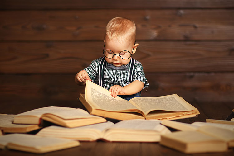 A baby boy flipping through pages of books.