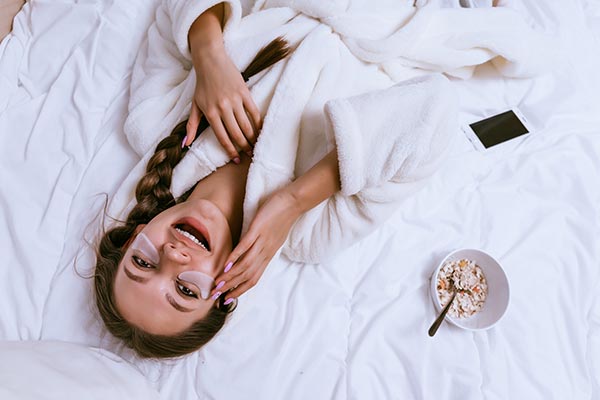 A girl lying on the bed after a face clean up.