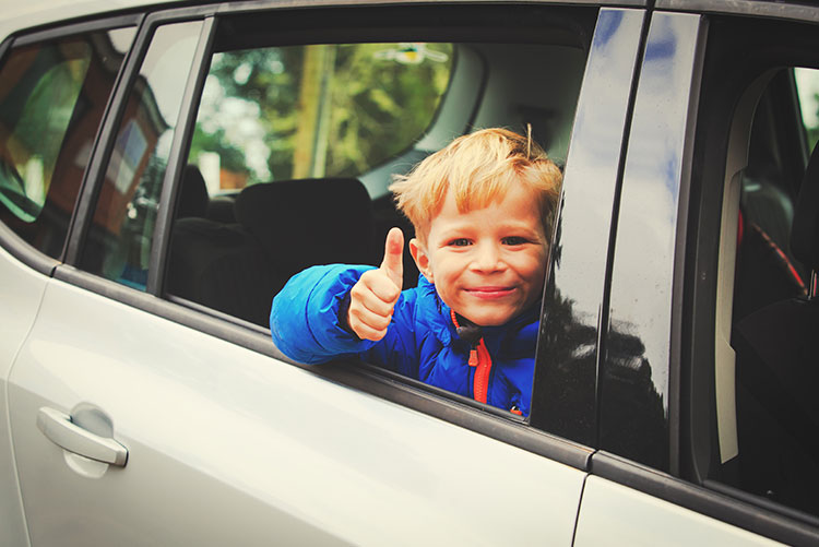 A guy giving a thumbs up while sitting in a car.