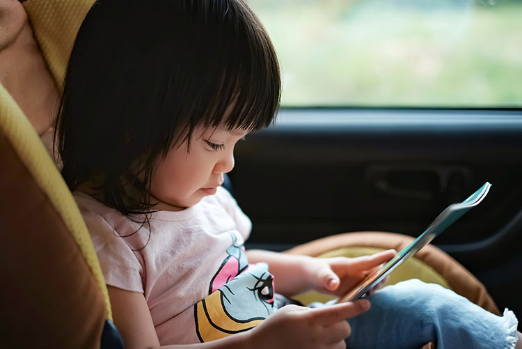 A girl reading a book in the car.