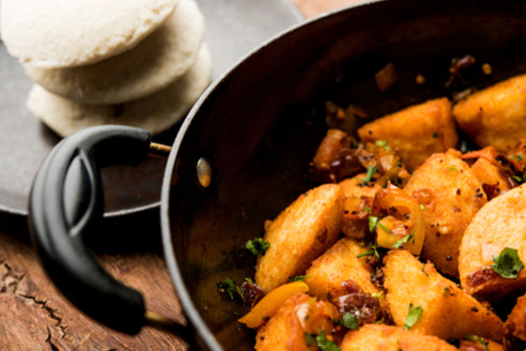 Fried idlis in a pan and blurred idlis in the background