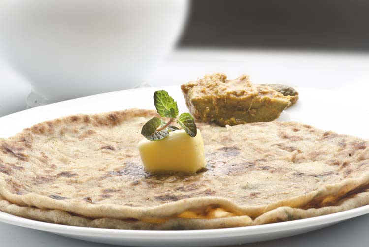 Aloo paratha served with butter and pickle on white plate!