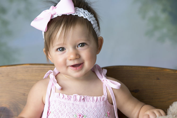 Beautiful infant girl in pink dress and headgear smiling!