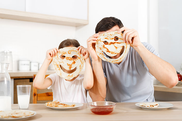 Father and daughter having fun at the breakfast table.