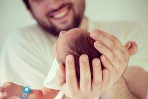 Father holding his newborn and smiling!