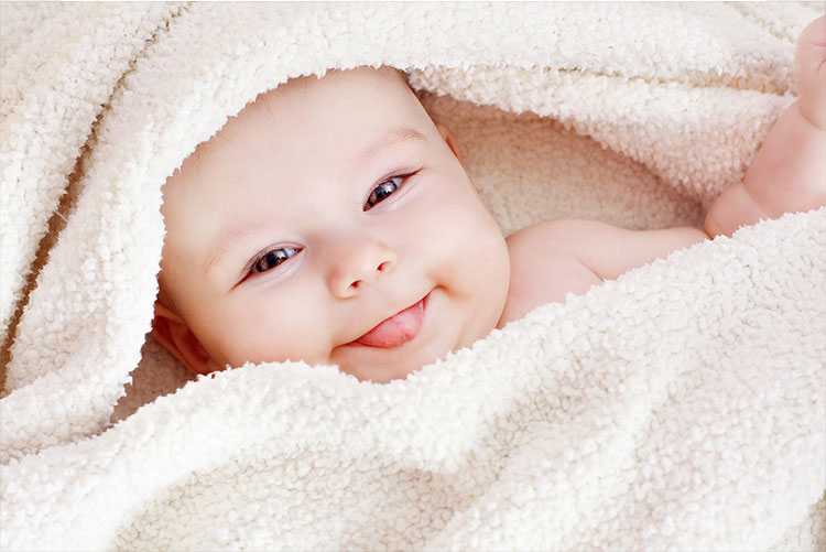 Infant wrapped in a towel smiling mischievously!