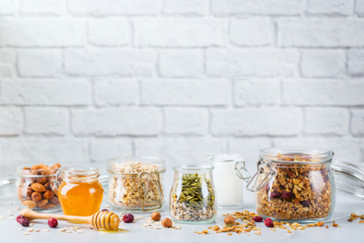 Jars of muesli, oats, pumpkin seed, honey, and almonds