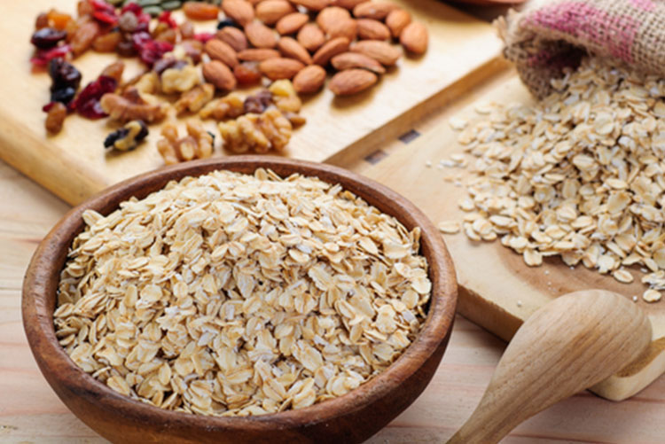 Bowl of oats next to dried fruits and berries