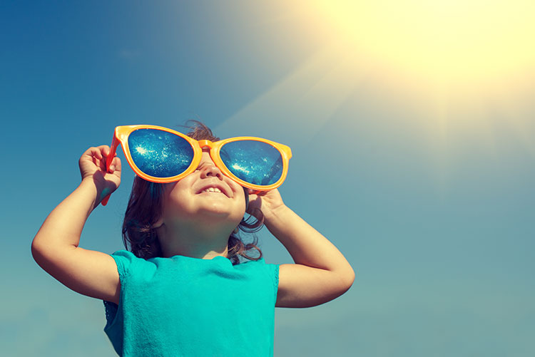 A boy holding up huge glasses to his eyes.