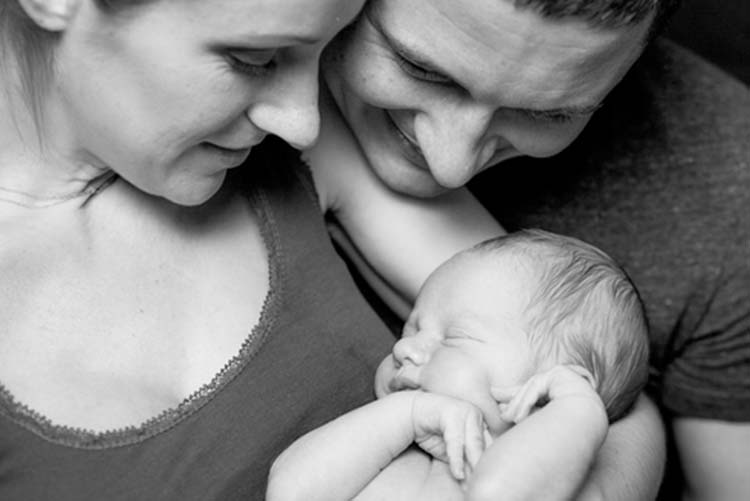 Black and white picture of mother and father holding the baby