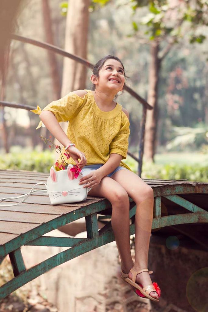 A girl enjoying her day sitting on a bridge.