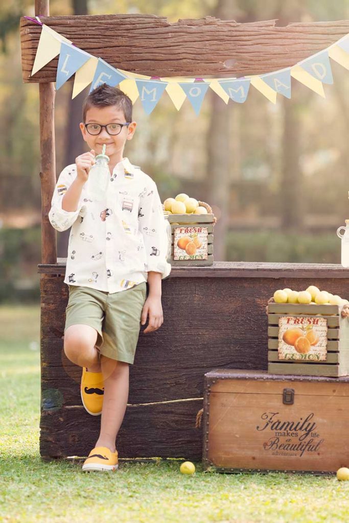 A boy sipping on lemonade on a hot summer day.