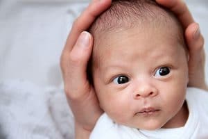 A newborn held in his mother's hands.