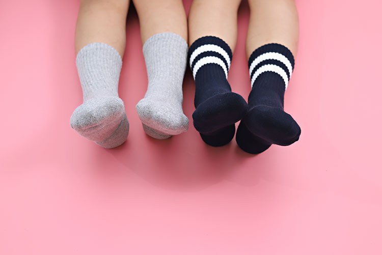 Two kids wearing socks - one grey and the other black.