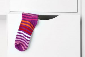 A colourful sock sticking out of a drawer.