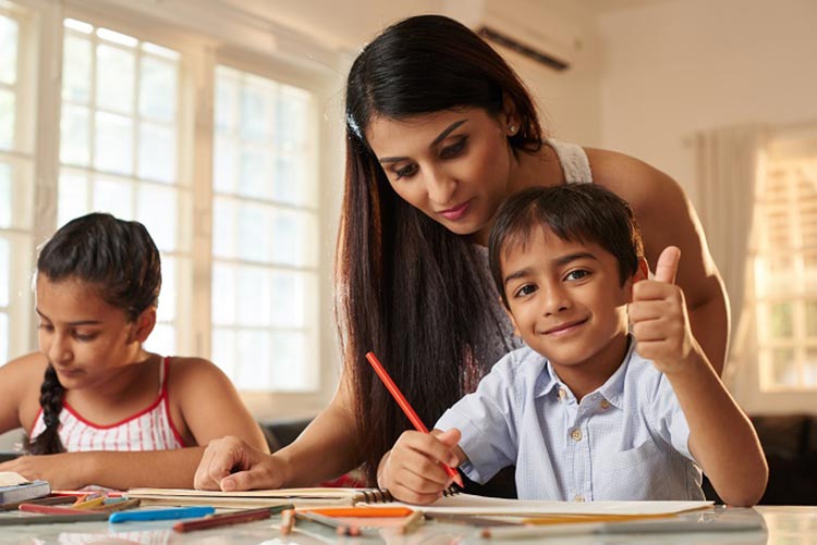 A son seems happy as his mom helps her kids in studies.