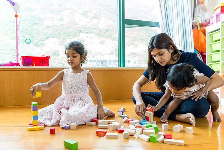 A mother playing with blocks with her children.