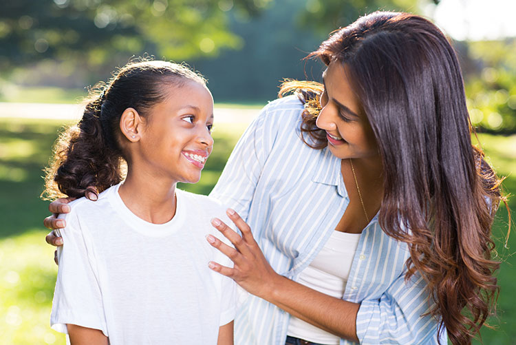 A mother smiling at her daughter as she smiles back.