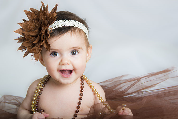 Infant wearing a beaded necklace and a floral headband!