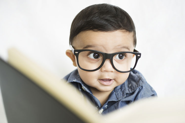 Adorable young boy wearing spectacles reading a book!