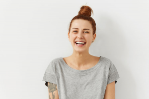 Cheerful woman standing against a white background with hair tied in a bun!