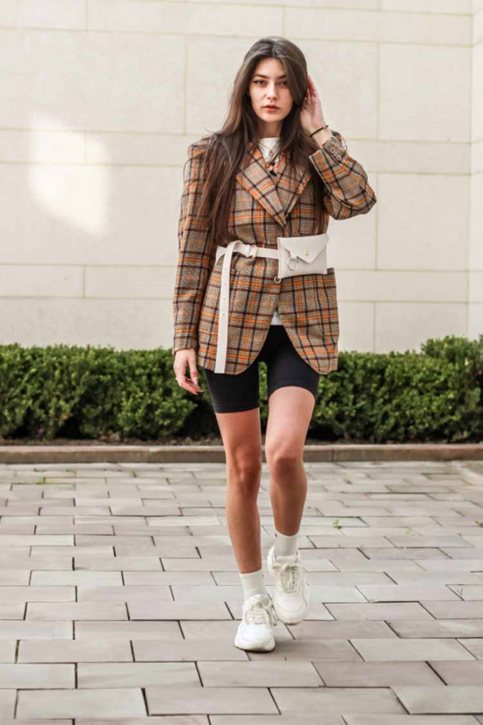 Model sporting bike shorts paired with a plaid print jacket, white belt, and white shoes!