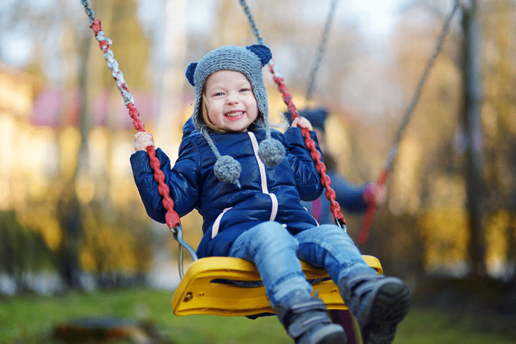Young cheerful girl playing on a swing during winter!