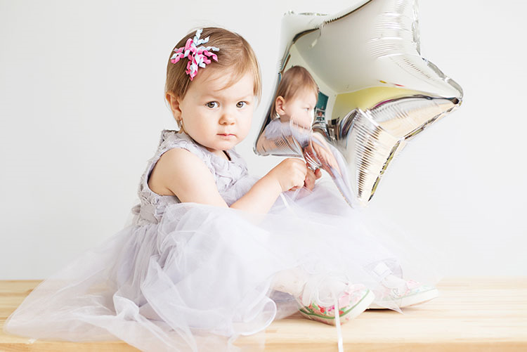 Cute toddler wearing a pretty dress and hairpin holding a silver balloon!