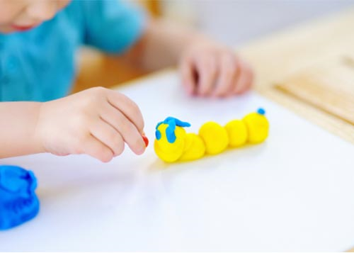 Toddler playing with a playdough caterpillar