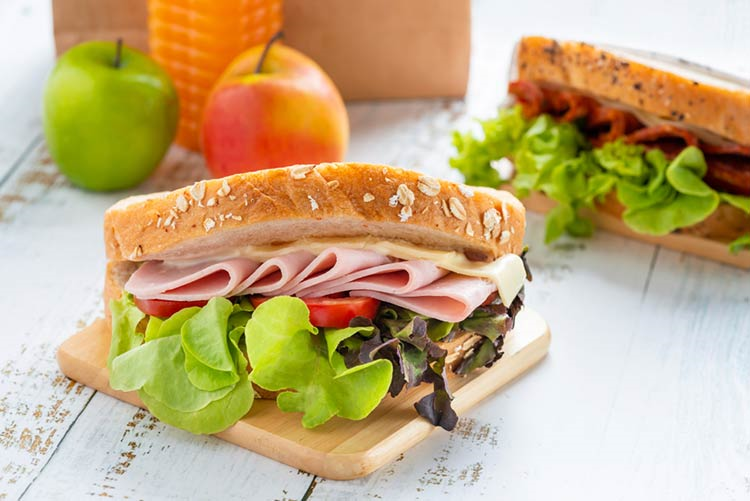 Club sandwich loaded with ham, tomatoes, and tomatoes served in a multigrain bread!