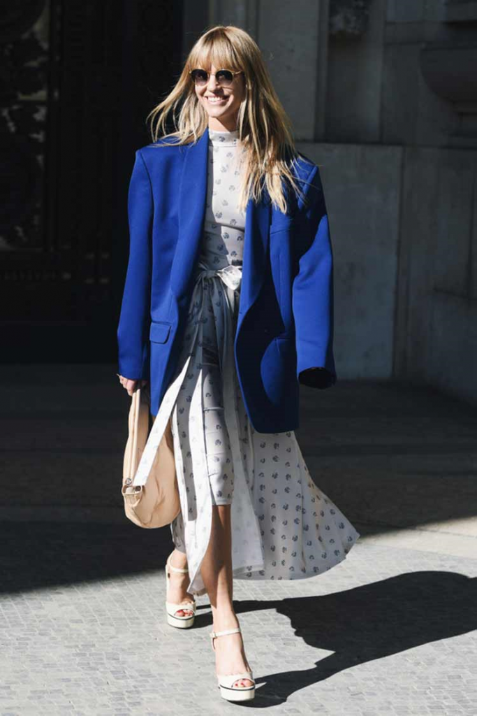 Woman wearing a white dress paired with Classic Blue blazer and white shoes!
