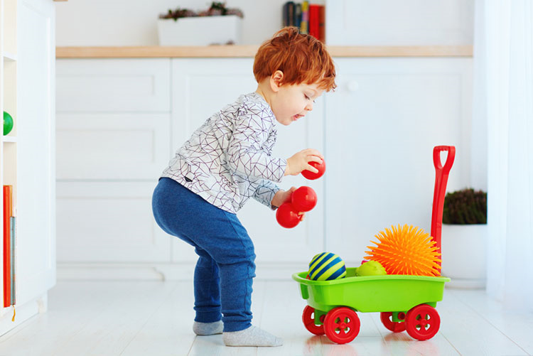 Toddler stacking his toys in a plastic trolley!