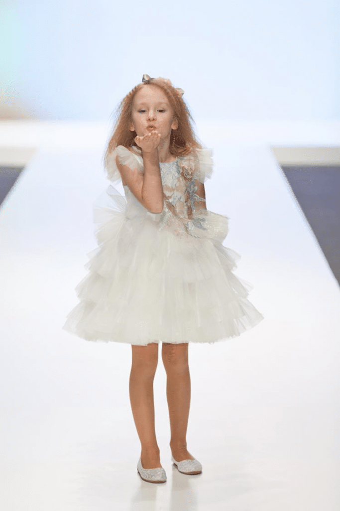 Pretty little girl blowing a kiss on a ramp, dressed in a white tulle dress!
