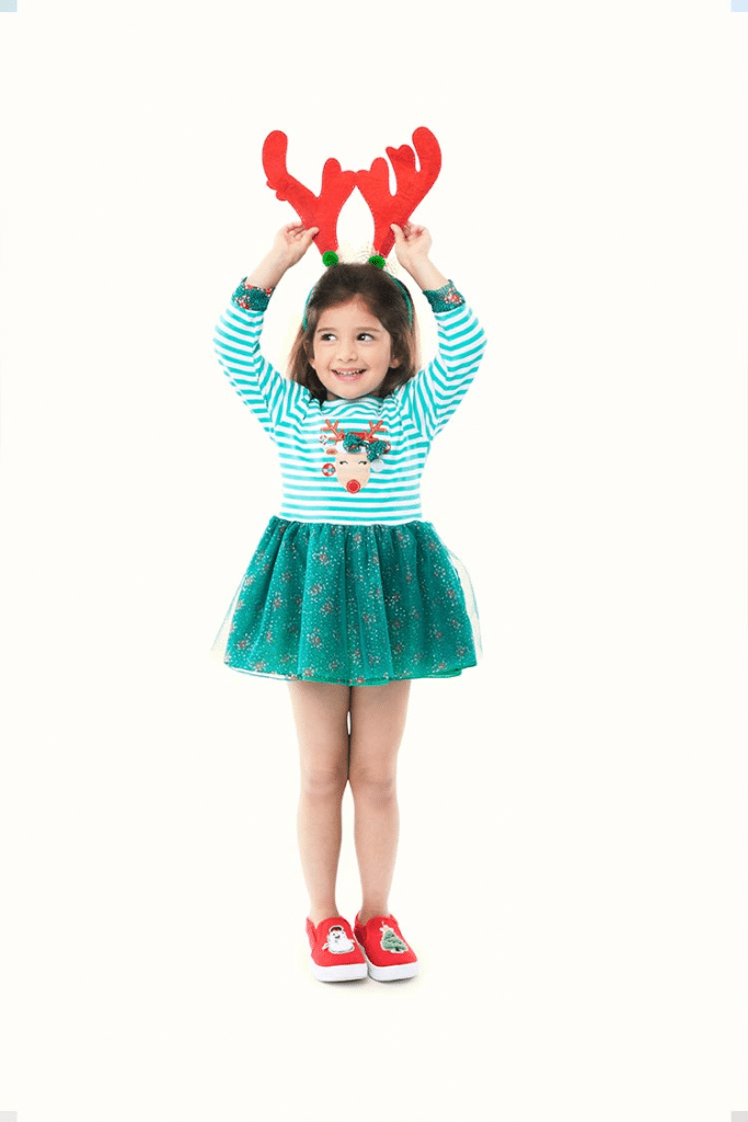 Adorable young girl wearing a striped reindeer Christmas outfit paired with a reindeer headgear!