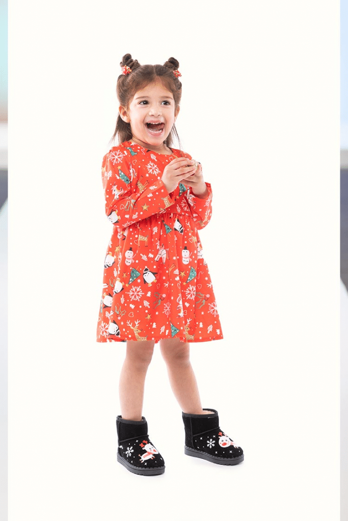 Young girl wearing an orange Christmas dress paired with black boots!