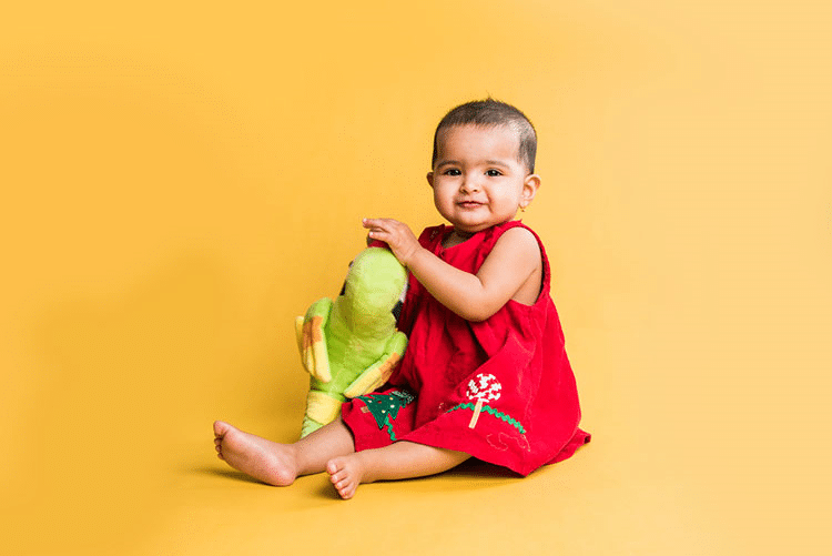 Infant girl in red dress playing with her plush toy!