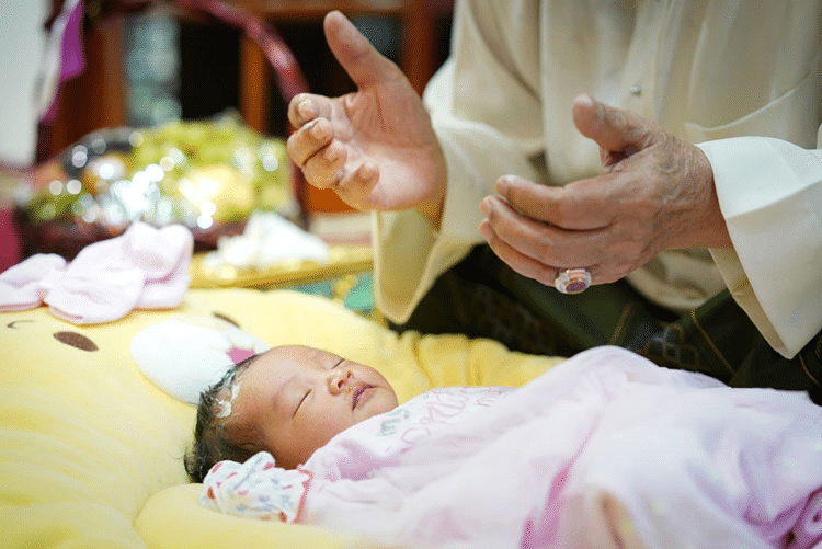 Muslim man praying for his baby, while the baby sleeps