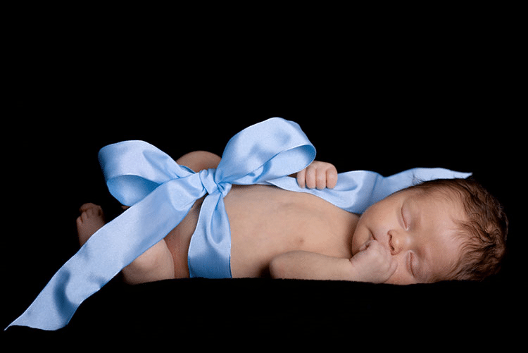 Newborn with a ribbon bow tied around the waist!