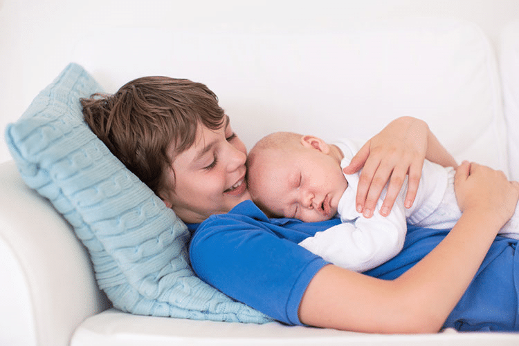 Infant sleeping on his bog brother!