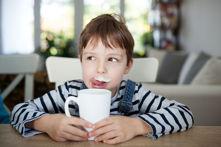 Cute young boy licking his milk moustache!