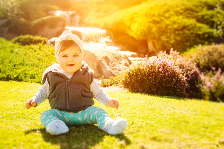 Adorable baby in winter attire sitting on grass!