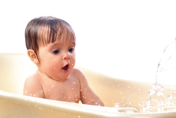Infant playing with water in a bathtub