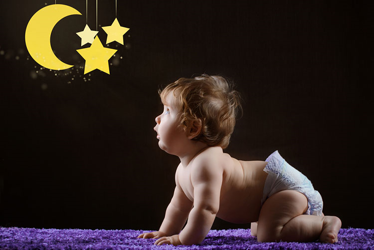 Crawling infant looking at a moon and stars wall-hanging!