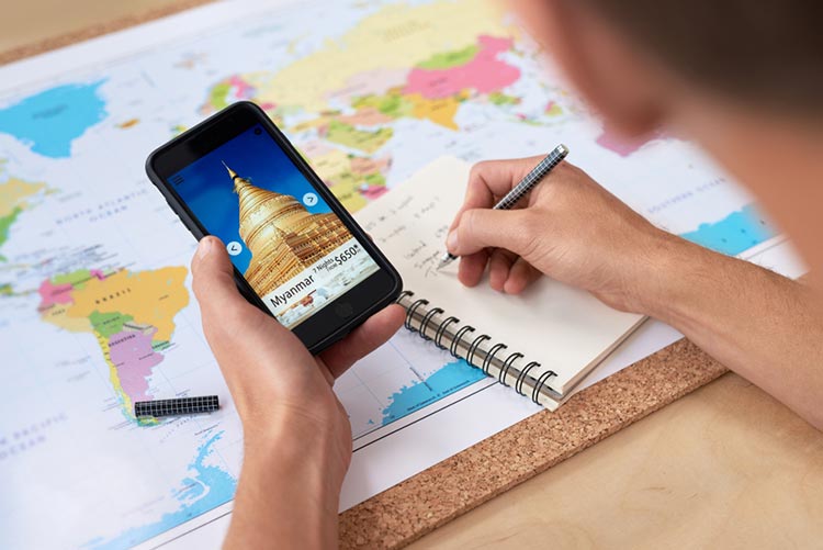 Person planning their travel with a planner, phone, and a map