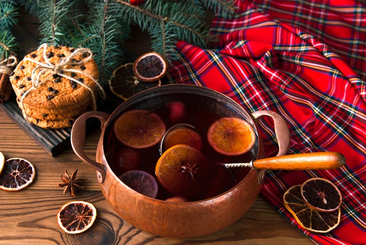 Spices, lemon slices, and orange slices in a pot of hot water