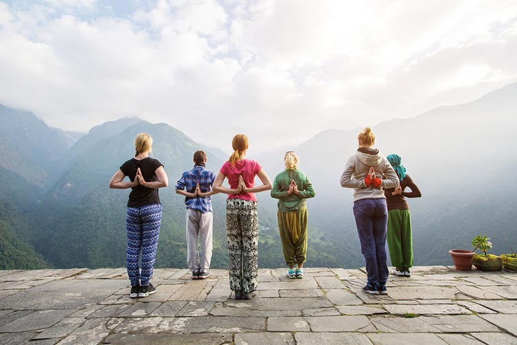 A group of people doing yoga in front of the mountains