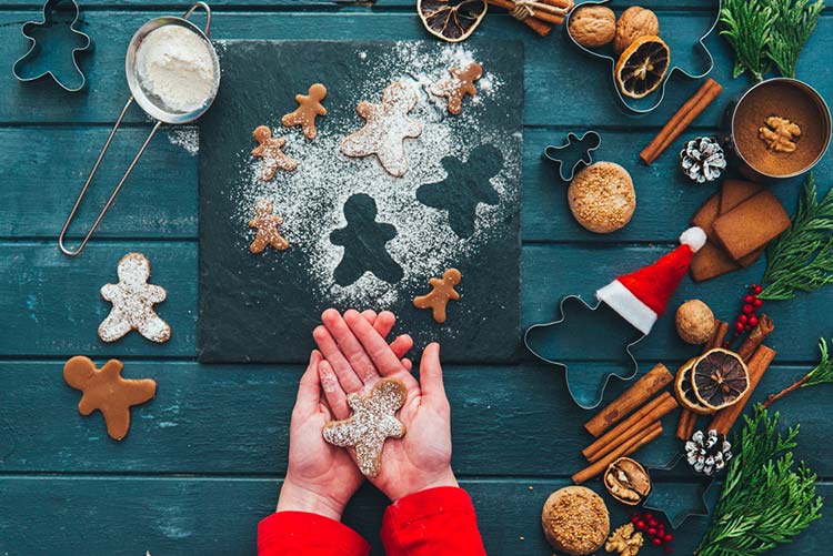 Person cutting cookies with all the ingredients lying around.